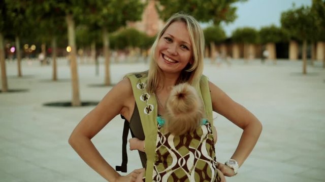 A woman with a baby in a sling or an ergo backpack.