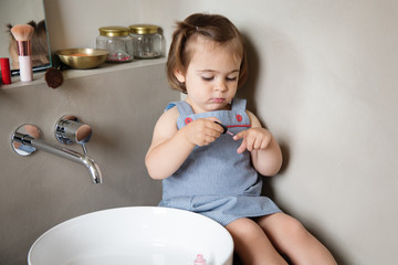Little girl painting nails in bathroom alone