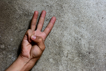 Three finger solute isolated on cement wall, hand language