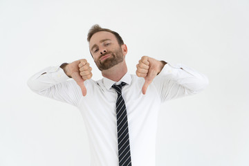 Disappointed office worker expressing his disapproval. Young Caucasian man with conceited face pointing thumbs down gesture. Failure concept