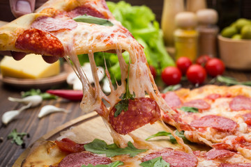 Pizza pepperoni with mozzarella cheese, salami and arugula on wooden background