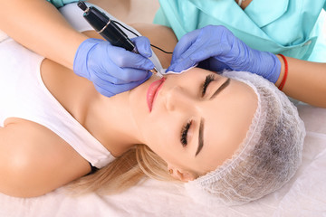 Obraz na płótnie Canvas Cosmetologist making permanent makeup on woman's lips