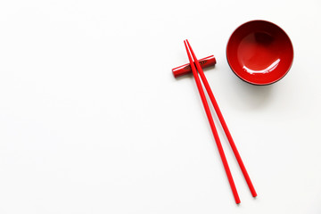 Top view of red chopsticks and red bowl on wood table background.Flat lay