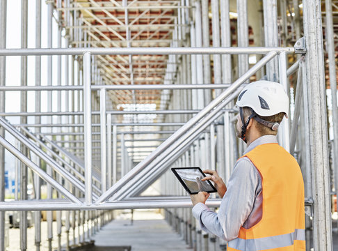 Architect with tablet wearing hard hat on construction site
