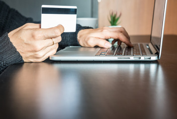 Hands of woman holding credit card and using laptop, online shopping concept.