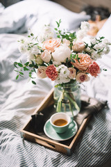 Delicious fresh morning espresso coffee in bed with a beautiful blossoming flower bouquet of...