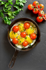 Fried eggs with tomatoes in frying pan