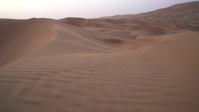 Wind chases the sand over beautiful dunes in the Rub al Khali desert before sunset United Arab Emirates stock footage video