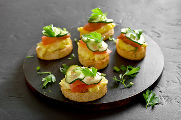 Canape with salmon, scrambled eggs and cucumber