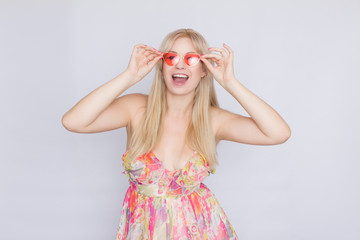 portrait of a young blond woman with long hair in a floral pink dress, and bright pink sunglasses