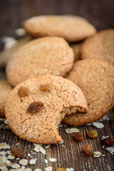 Homemade oatmeal cookies with raisins, cinnamon with milk on dark wooden background.
