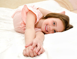 Adorable smiling little girl is resting on a bed