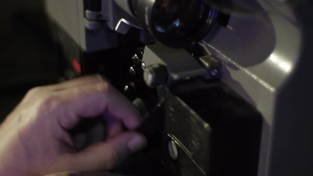 The mechanic charges the film in an old film projector. Close-up of a reel with a film