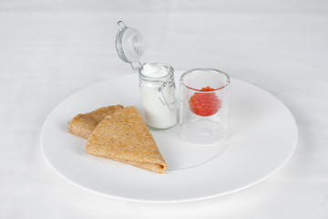 Pancakes with sour cream and red caviar.