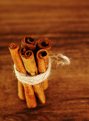 Cinnamon sticks, tied with jute rope on brown wooden background in rustic style