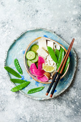 Vegan asian udon noodles soup bowl with ginger and mushrooms broth, tofu, snap peas, zucchini,...