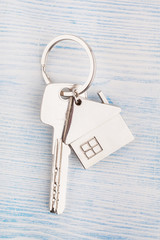House key with trinket house on a wooden background