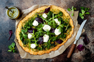Cauliflower pizza crust with pesto, kale, mozzarella cheese and greens
