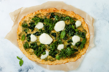Cauliflower pizza crust with pesto, kale, mozzarella cheese and greens