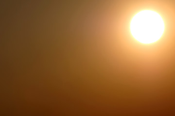 Abstract bright circle of light on a yellow background. Radial gradient from light yellow to orange-brown. A solar disk in the upper right corner of the frame at sunset.