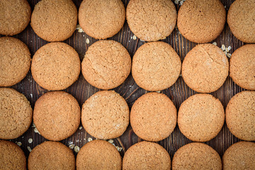 Homemade oatmeal cookies with raisins, cinnamon with milk on dark wooden background.
