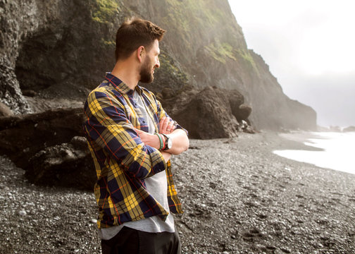 guy tourist standing on the beach at sunset in Iceland in checkered shirt