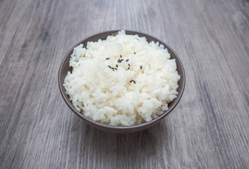 Japanese rice in brown small bowl on wood background