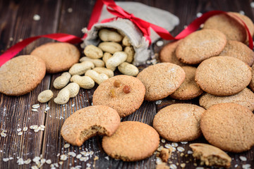Homemade oatmeal cookies with raisins, cinnamon with milk on dark wooden background.