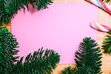 Christmas candy cane and fir tree branch on wooden background. Xmas presents concept with copy space. Christmas border or greeting card