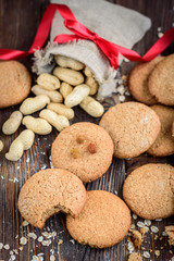 Homemade oatmeal cookies with raisins, cinnamon with milk on dark wooden background.