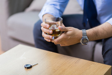 alcohol abuse, drunk driving and people concept - close up of male driver hands with whiskey glass and car key on table