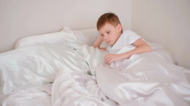 Seven-year-old a boy quietly laying in bed in his room