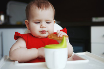 baby in a red dress is sitting on a child's chair