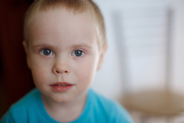 Child boy with blue eyes in a T-shirt expresses emotions