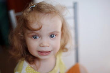 Baby girl with blue eyes and red hair in a T-shirt expresses emotions smiling