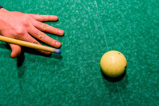 Player arm with the cue and ball on the green cloth. Russian billiard. Top view