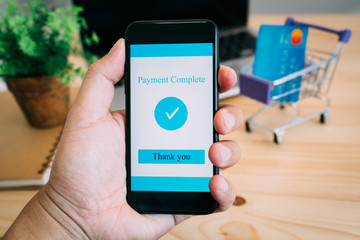 Hands using smartphone and laptop computer for online shopping at home