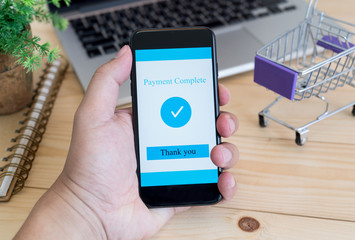 Hands using smartphone and laptop computer for online shopping at home