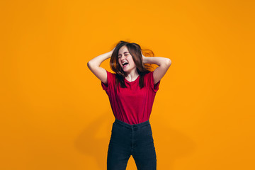 The happy teen girl standing and smiling against orange background.