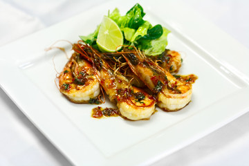royal shrimps grill in sauce with lettuce and lime on white plate