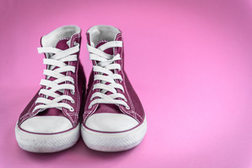 Pink sneakers on pink background with copy space.