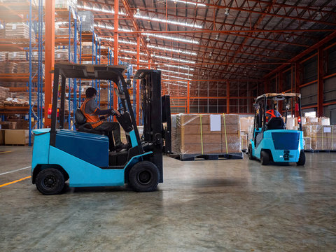 Forklift is handling cargo on pallet  in large warehouse.