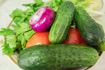 washed vegetables - cucumbers, tomatoes, red onion and parsley in a plate, ready for being chopeed for the salad, top view