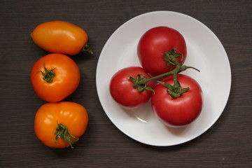 Спелые помидоры на тарелке и рядом