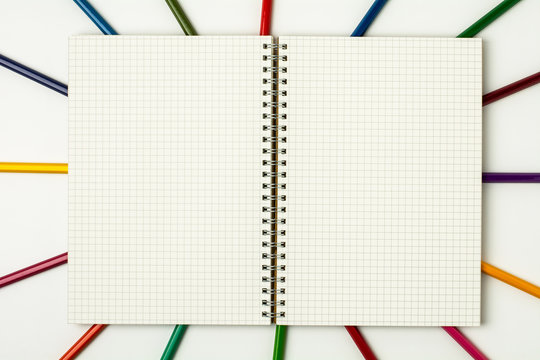 grid book and colored pencil on white background