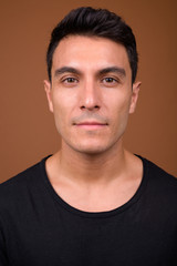 Fototapeta premium Young handsome Hispanic man against brown background