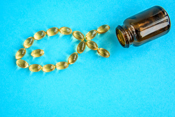 Fish oil capsules on blue background, fish shape