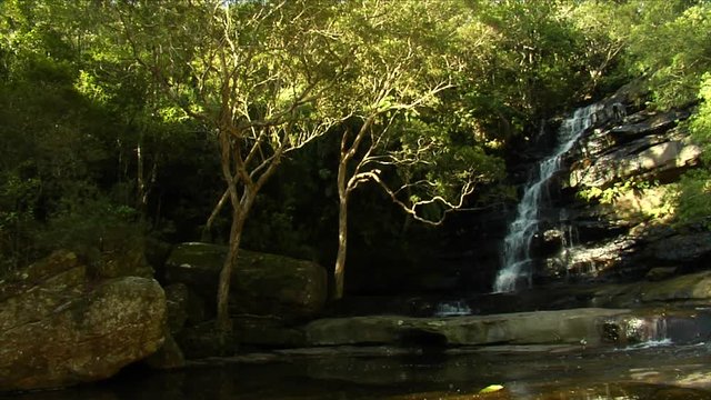 Slow motion tracking shot moving left to right showing a large waterfall in Australia
