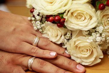 Obraz na płótnie Canvas Groom and bride's hands with wedding rings beside bouquet