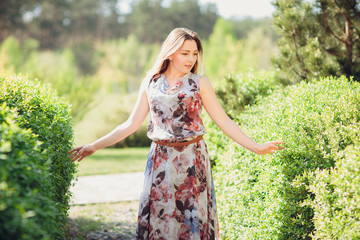 Young woman enjoying spring in the green field with blooming trees